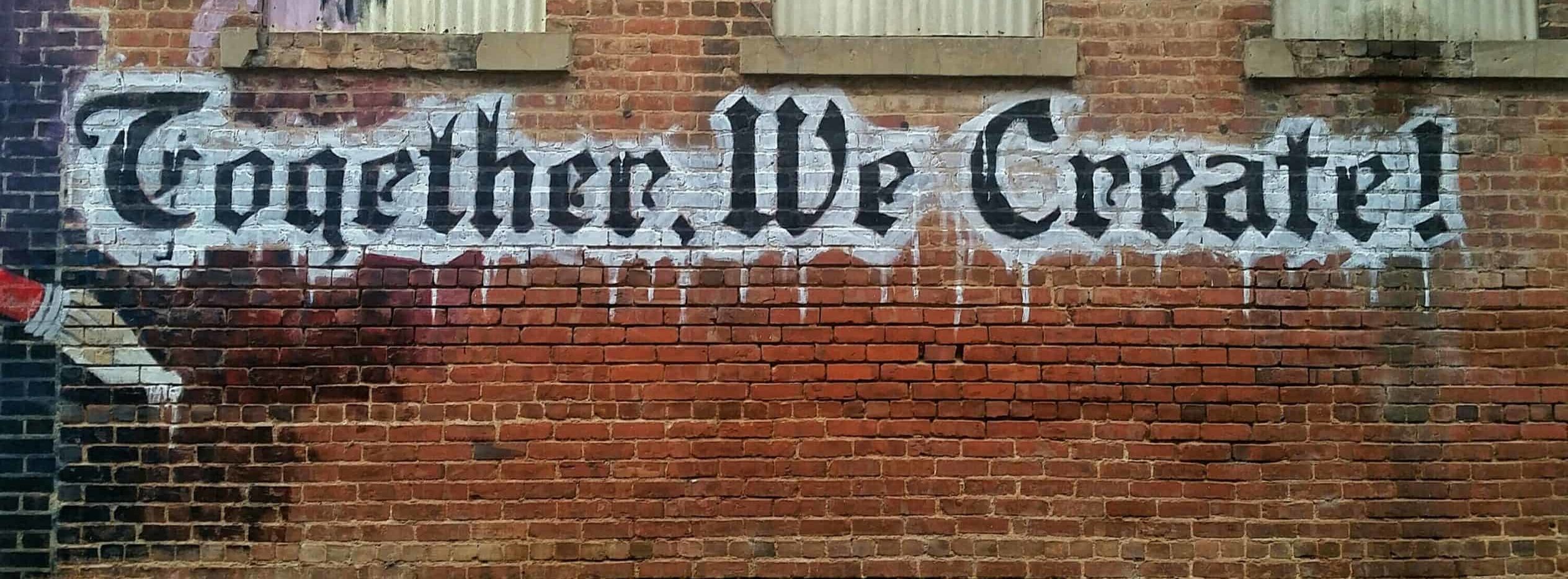 graffiti on a brick wall that says "Together we create"