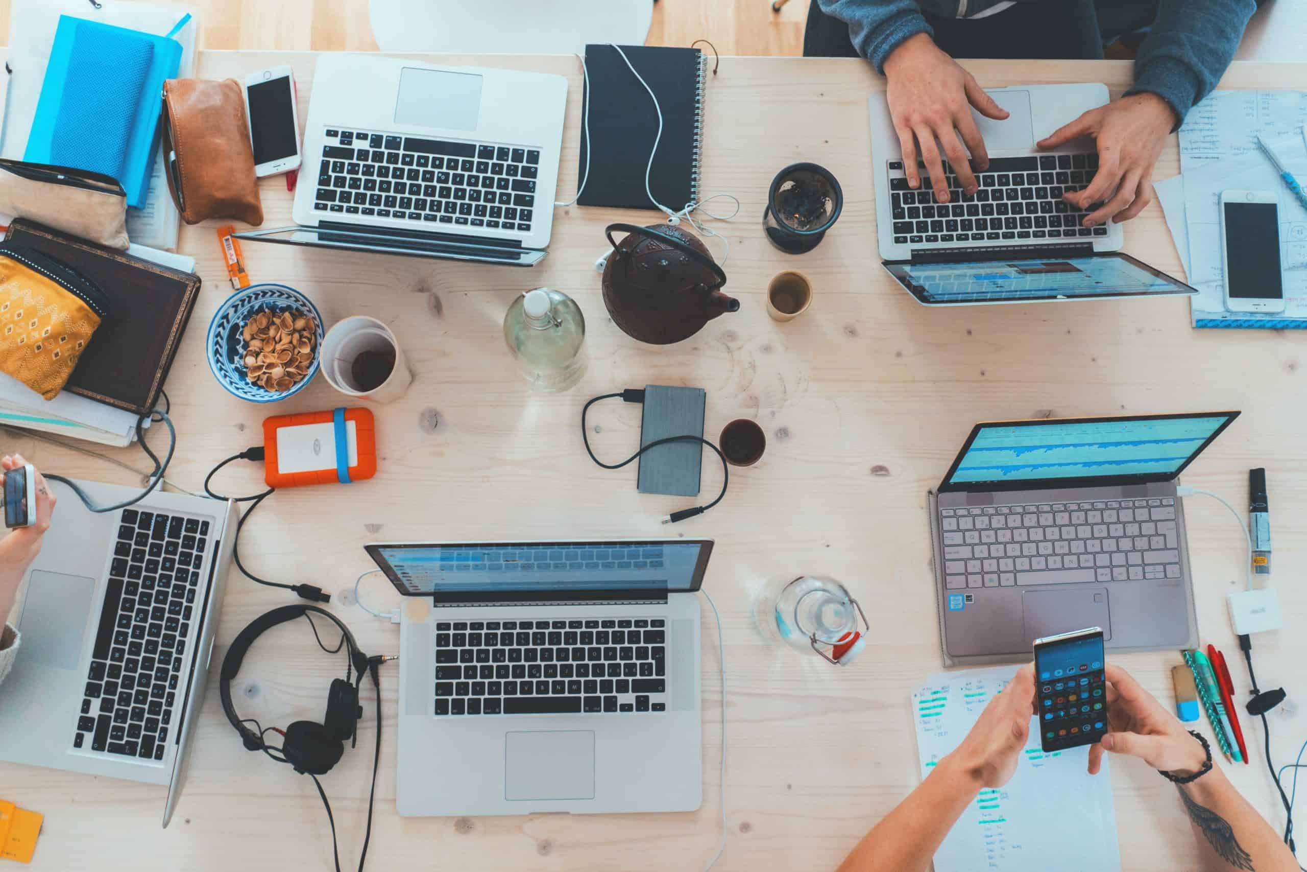 hands and laptops of software developers at a wooden desk shot from bird's eye view