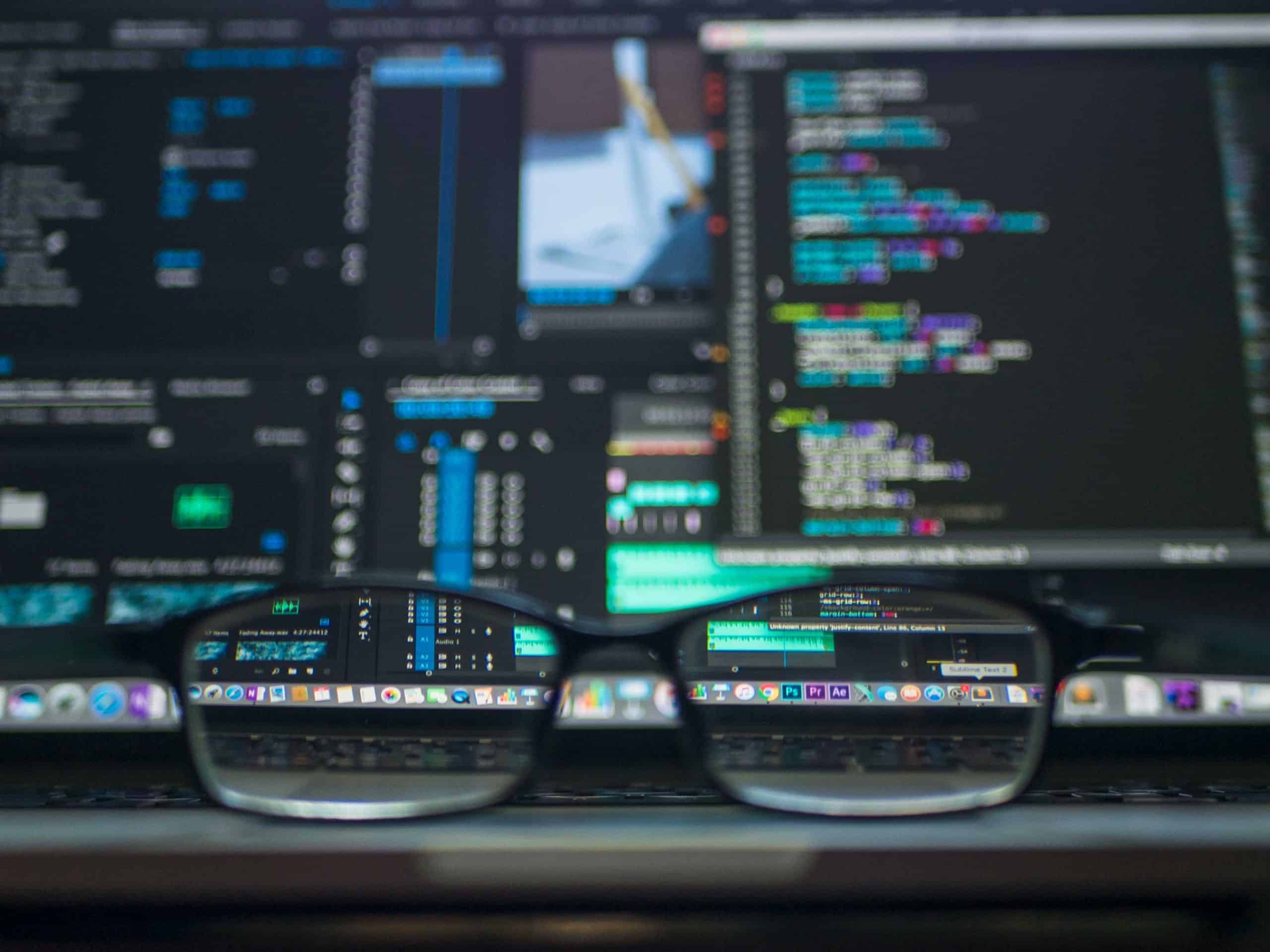 code lines on screens and a pair of glasses